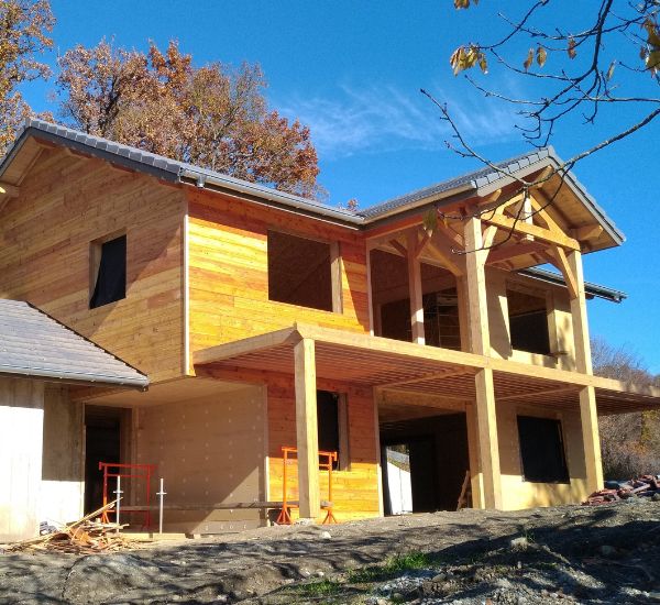 Avancement du chantier d’une maison bois, avec les parois installées et la forme de l’habitation bien dessinée